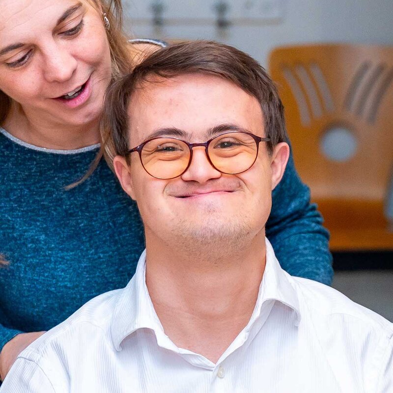 Ein Mann mit Einschränkungen wird von einer Pflegekraft betreut